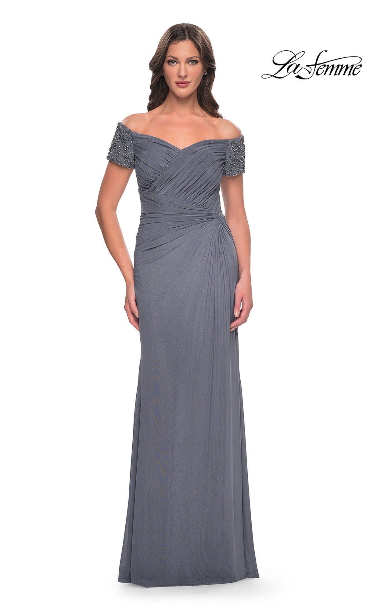 A woman wears the Long Formal Dress: La Femme 30057 in gunmetal, featuring off-the-shoulder beaded short sleeves and a floor-length skirt, standing against a white background.